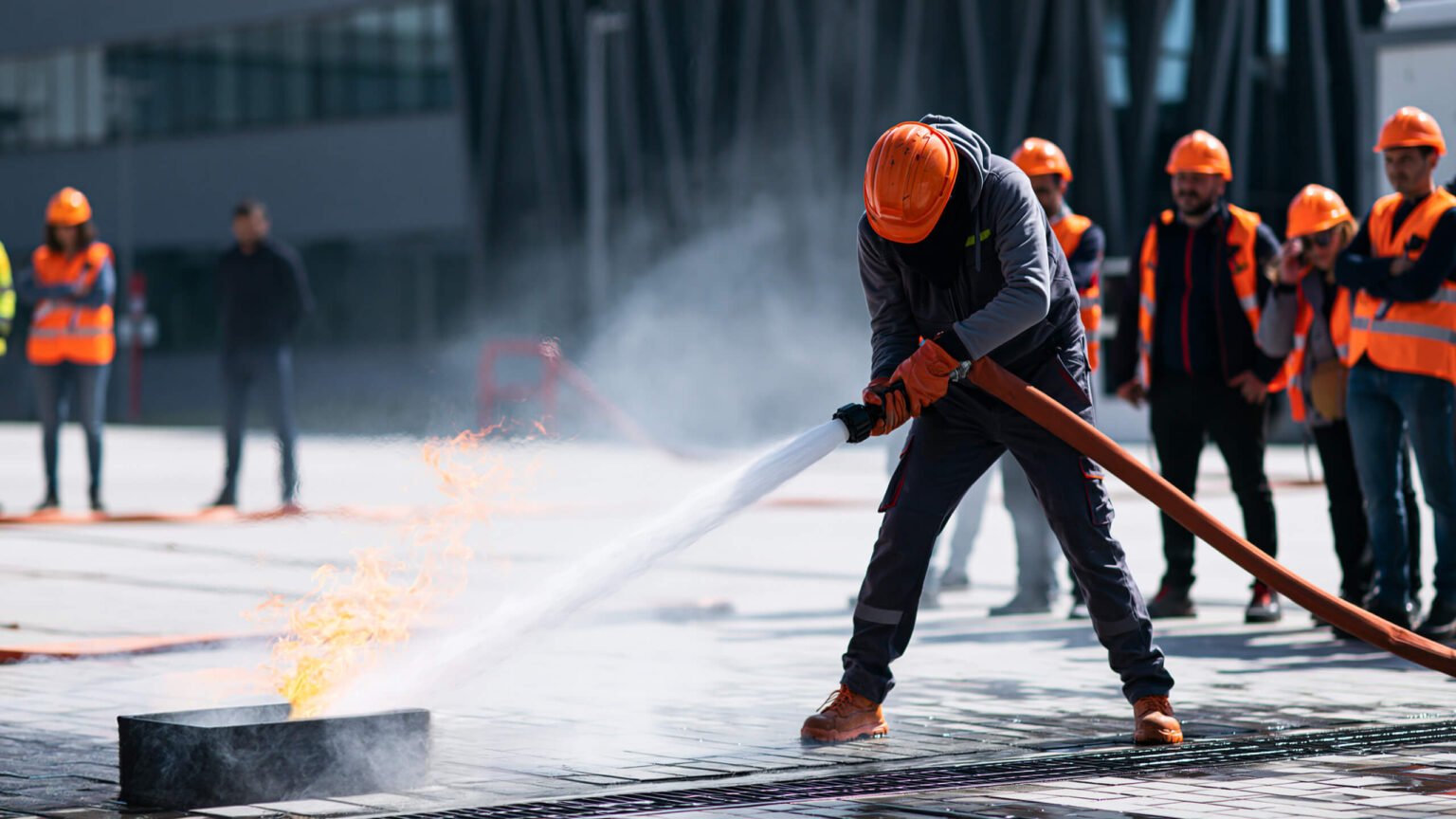 Immagine di una persona che spegne un fuoco controllato. Formazione sulla sicurezza con prova pratica.